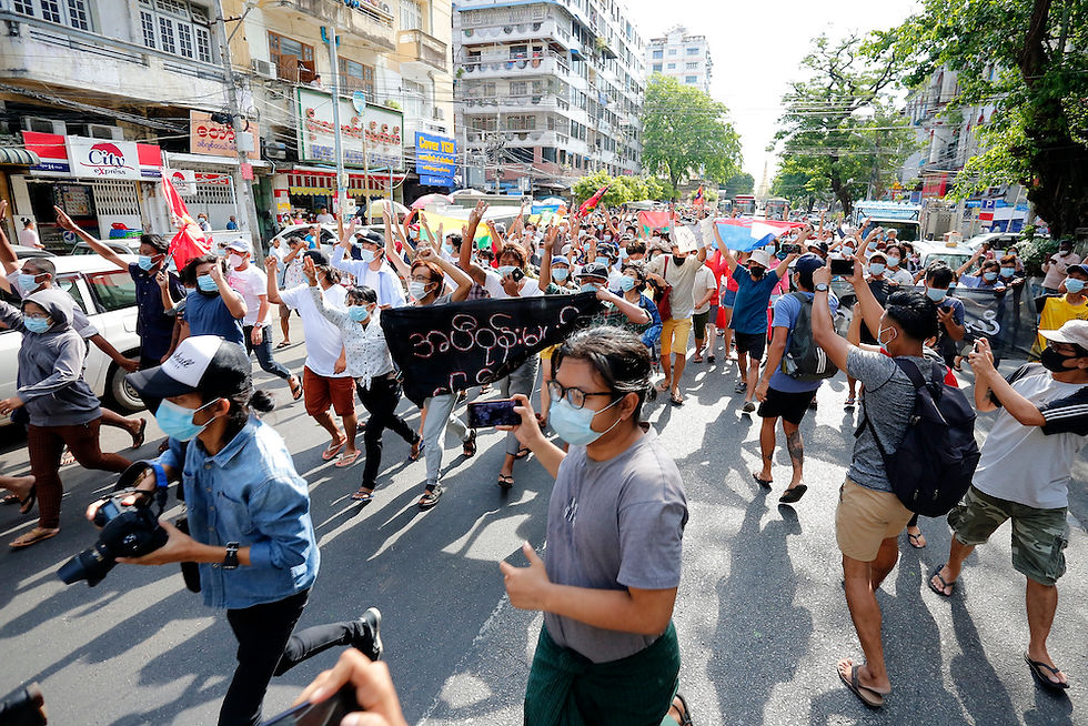 Myanmar journalists take cover during a flash mob protest against the February 2021 military coup near Sule Pagoda in central Yangon on May 6, 2021. (Credit: AP)