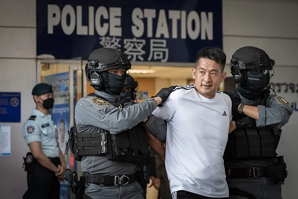 She Zhijiang is frogmarched out of Suvarnabhumi Airport Police Station in Bangkok on November 12, 2025, for extradition to China. / AFP