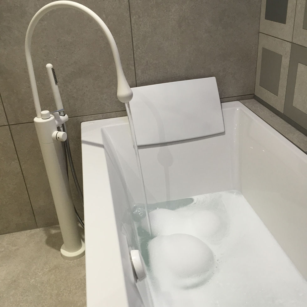 Salle de bain moderne avec carreaux à motifs, double vaque, meuble imitation chêne et baignoire avec mitigeur sur pied.