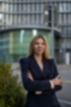 Susanna Riebel steht leicht seitlich zur Kamera, lächelt freundlich und verschränkt die Arme locker vor dem Körper.