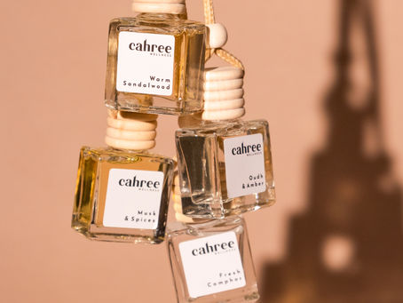 Cahree Wellness car perfumes with wooden caps stacked against a warm beige background
