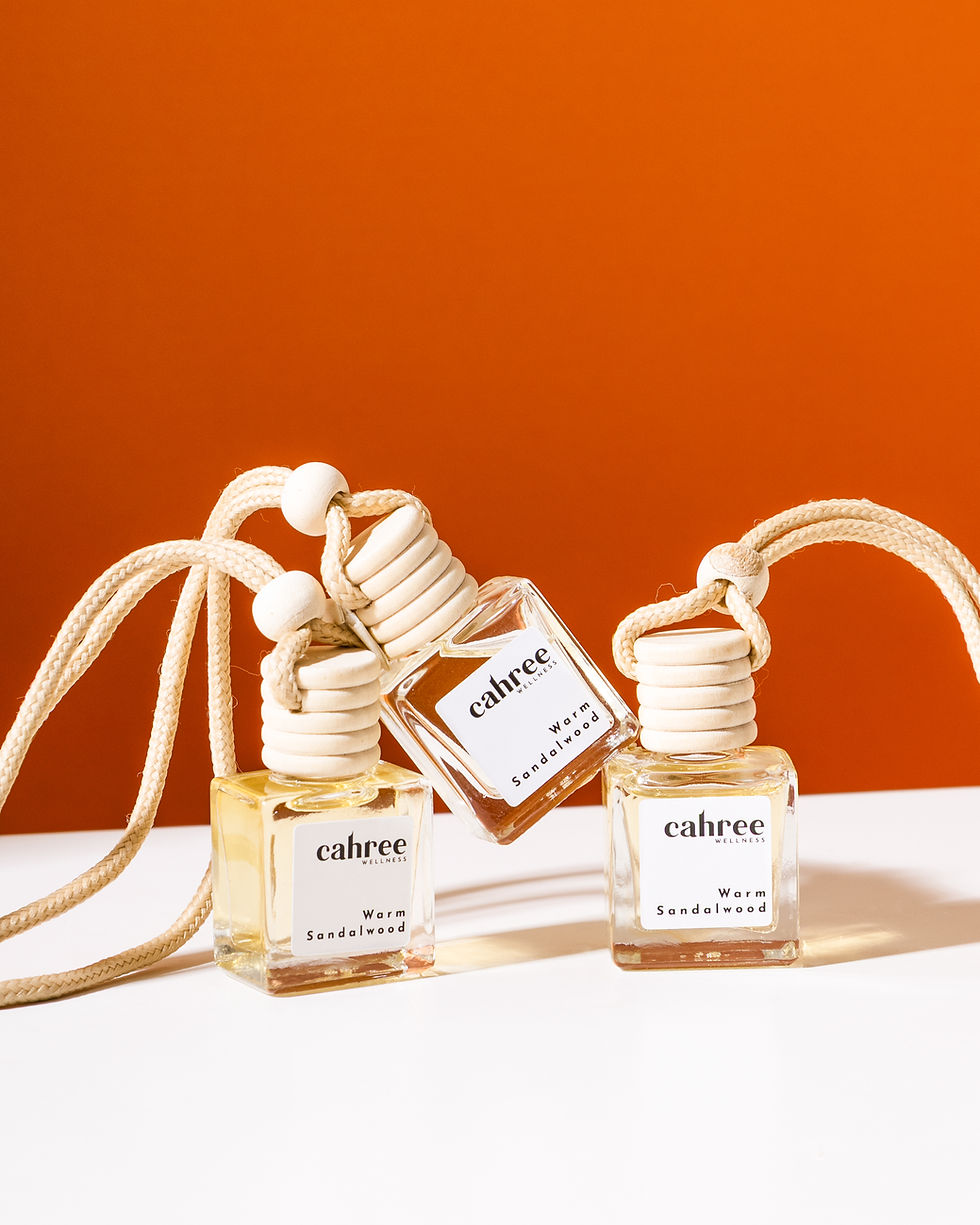 Cluster of Cahree car perfumes with wooden caps styled against a bold orange background