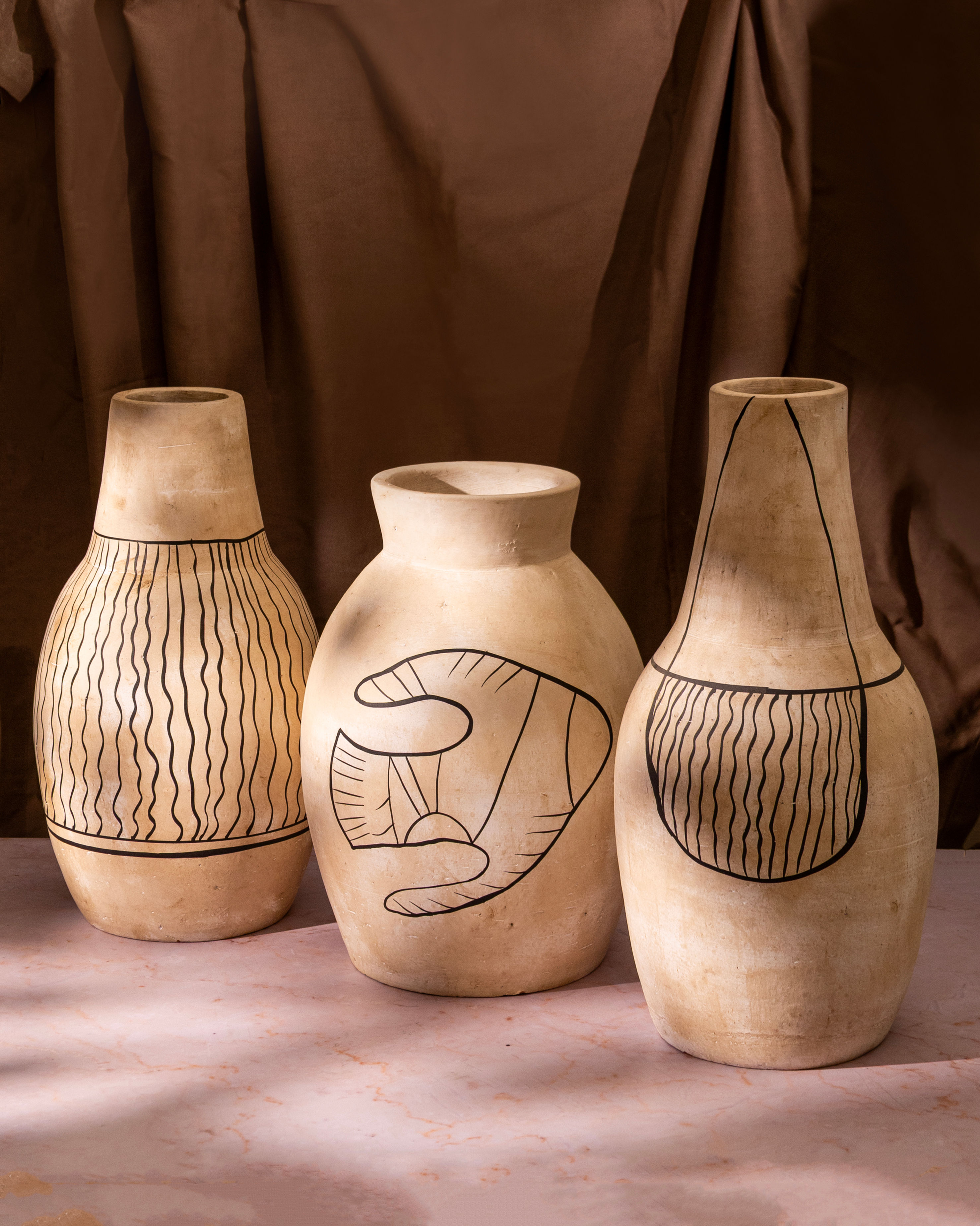 Set of three matte ceramic decorative vases with hand-drawn patterns in neutral tones, styled against a warm minimal backgrou