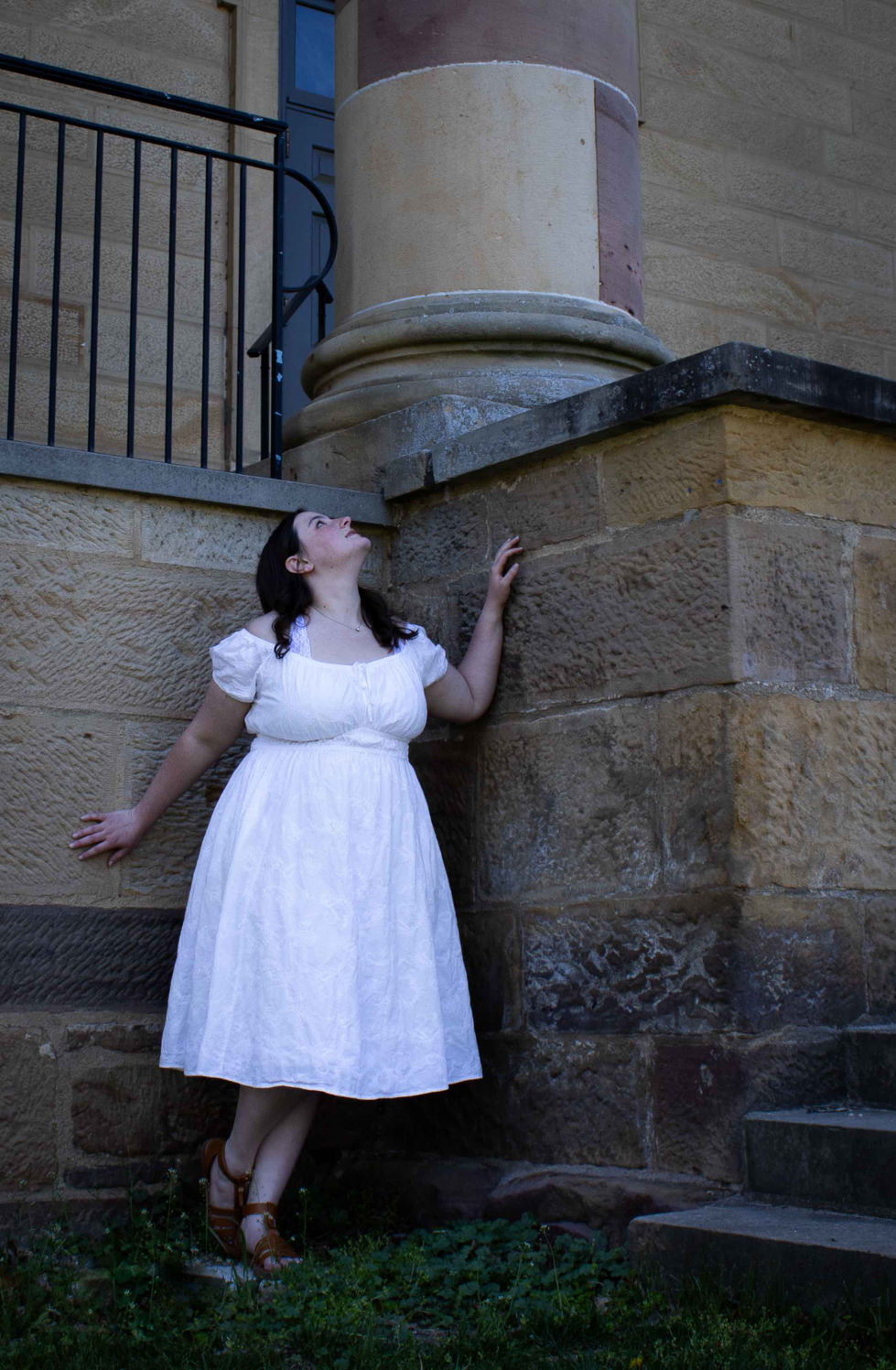 Marhin standing by castle steps in a white dress
