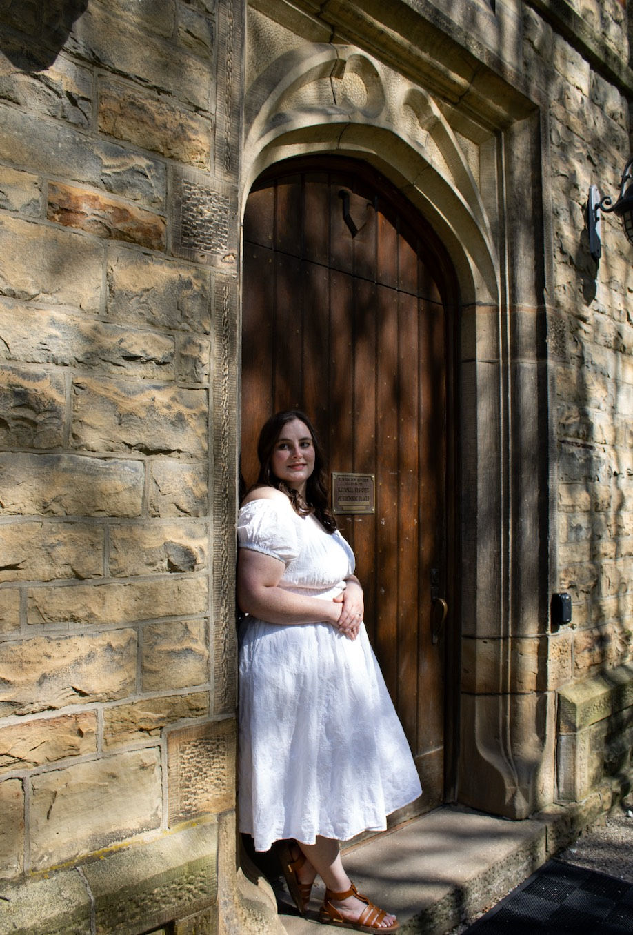Marhin standing in a white dress in front of a castle door