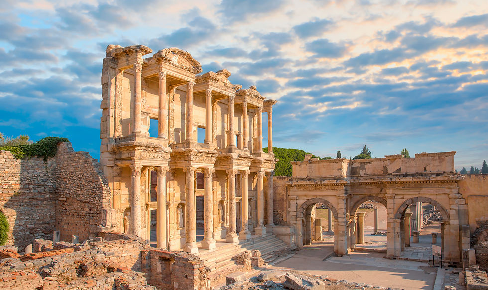 Ancient ruins with tall, intricate stone columns and arches under a partly cloudy blue sky, evoking a sense of historical grandeur.
