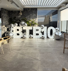 Steel marquee letters spelling company acronym at 10 year corporate anniversary event with mirror ball decorations