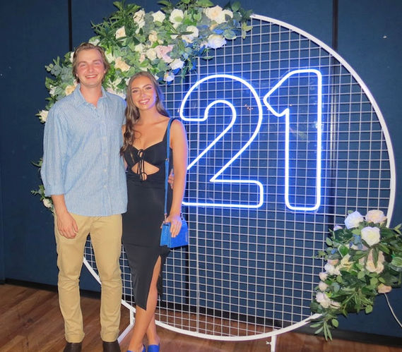 21 neon sign with white circular mesh stand and spring flower garland at Darling & Co Swayzee Room