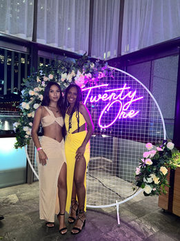 Twenty One neon sign on a white circular mesh stand with spring style faux florals at Bar Pacino