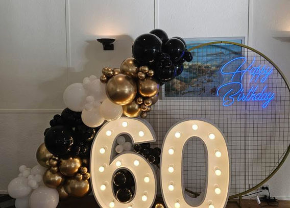 Signature 60 1.2m light up number set with black circular mesh stand, balloon garland and 'Happy Birthday' neon sign