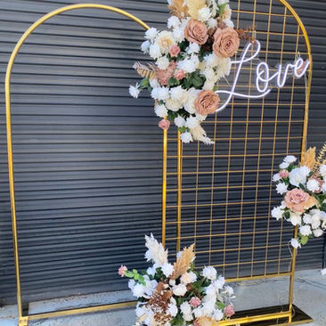 Gold Mesh Arch with mocha and white rose flower garland and 'Love' neon sign for wedding or engagement party
