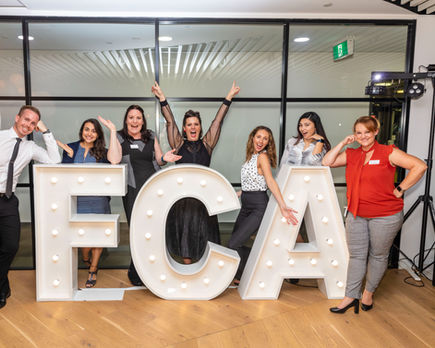 Corporate acronym light up letters surrounded by excited staff at company celebration event