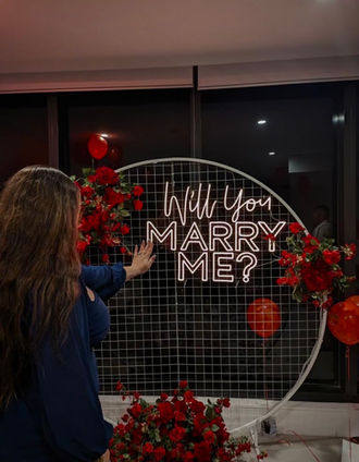 Will you Marry me? neon sign with white circular mesh stand and red rose flowers