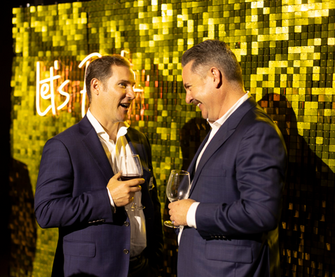 Gold shimmer wall with 'Let's Party' neon sign for corporate event