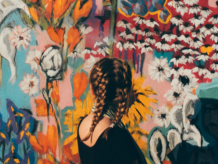 Woman with braided hair in front of a bright floral mural