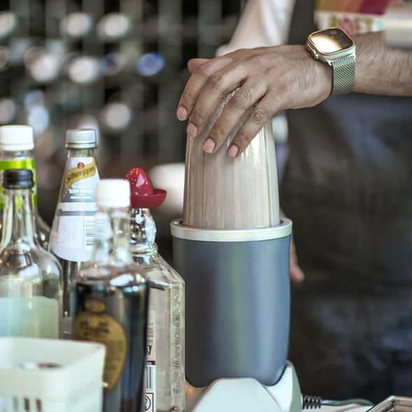 Bartender preparing a fresh drink at Poetry – The Beauty of Indian Flavours, blending ingredients behind the bar for a handcrafted beverage