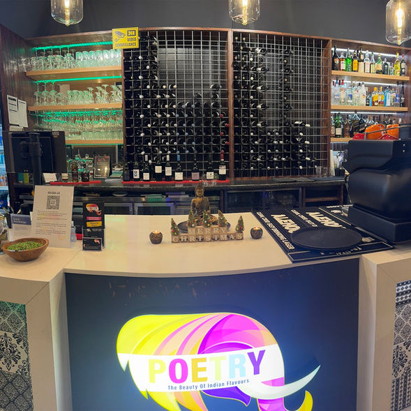 Front counter of Poetry – The Beauty of Indian Flavours with wine display, glass shelves and festive décor at the restaurant bar area