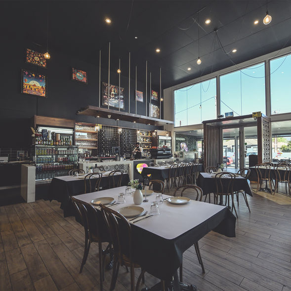 Modern Indian restaurant interior with elegant wooden seating, large glass windows, warm lighting and a stylish bar setup at Poetry – The Beauty of Indian Flavours