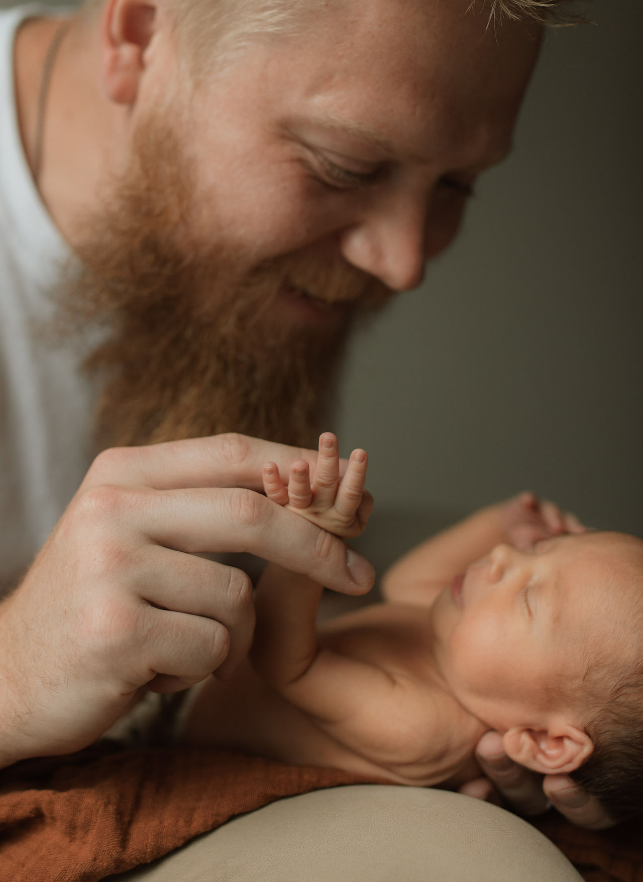 a newborn baby holds dad's fingers