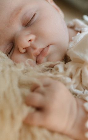a newborn baby sleeps on sheep rug