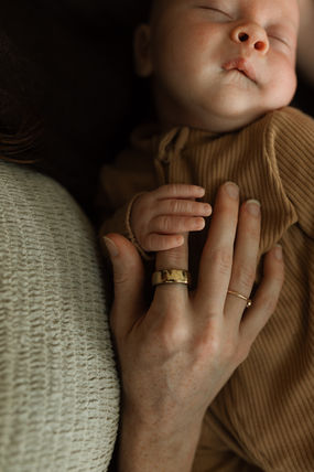 mother holds newborns finger