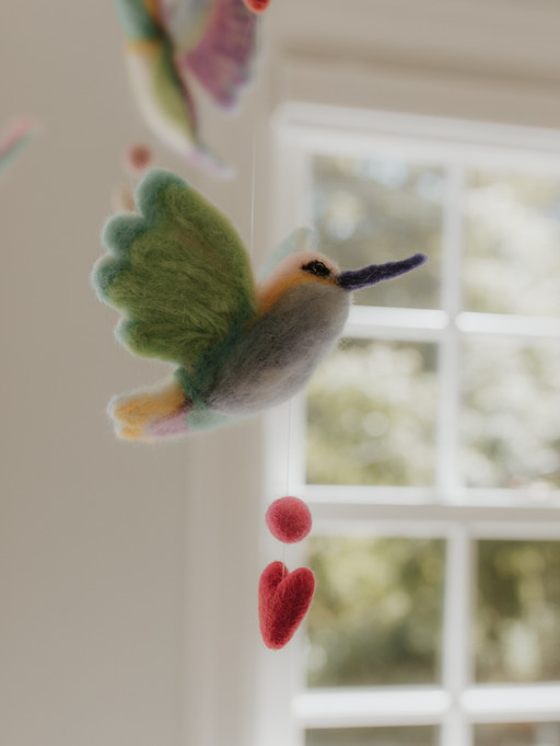 a need felted hummingbird is part of a baby crib's mobile