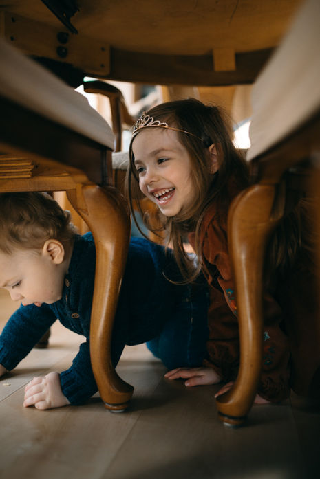 kids crawl under dining table during an in-home family photography session in Sandy, Oregon