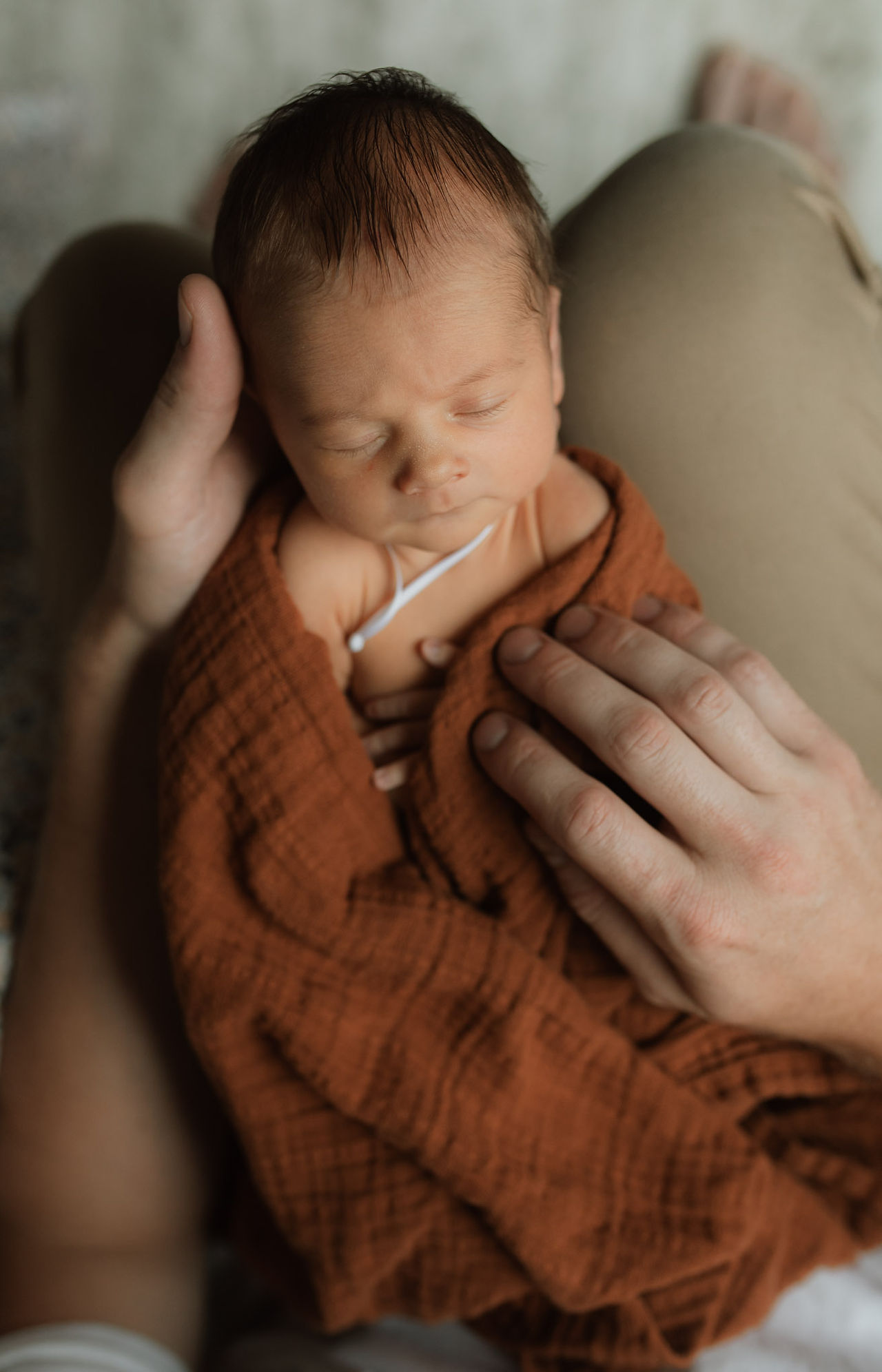 a father holds his newborn baby in his lap