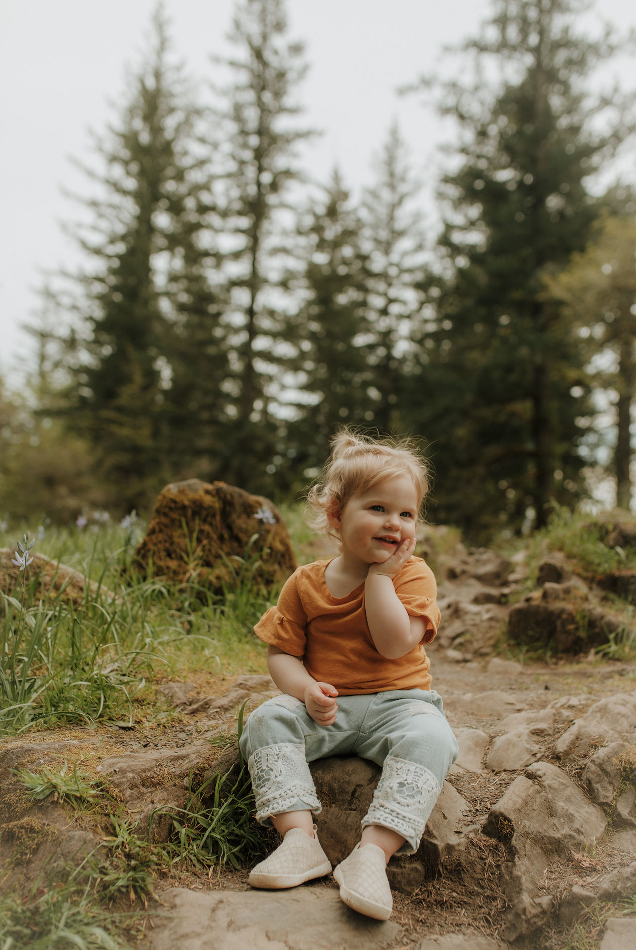 girl sits on trail in the middle of a wildflower field near Vancouver, WA