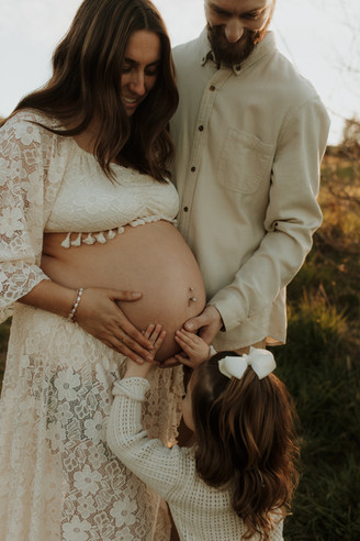 daughter puts hands on mama's pregnant belly