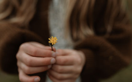 a child holds a flower between her fingers