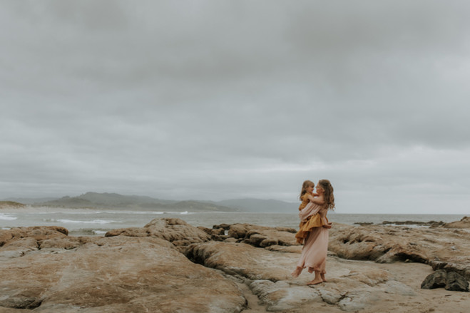 family dances on rocks on the oregon coast