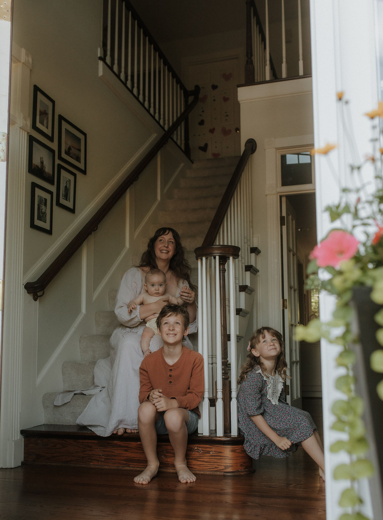 family sits on stairs and looks out front door