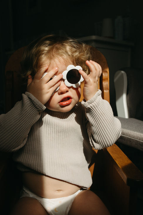 toddler reaches for sunglasses near in-home window near Sandy, Oregon