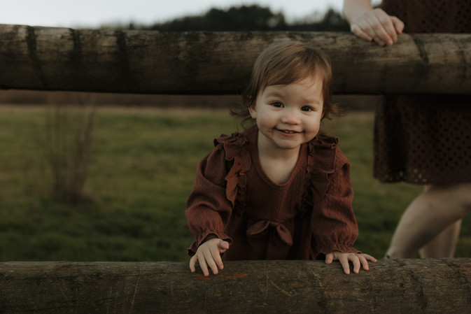 baby smiles at camera through wooden fence
