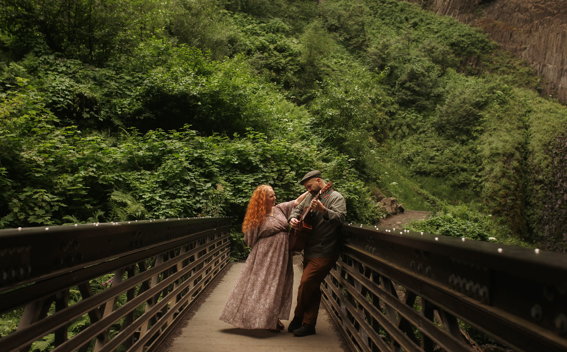 a couple plays guitar on a hiking bridge in the Columbia river gorge