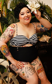 Tia in a retro swimsuit, showing off her tattoos