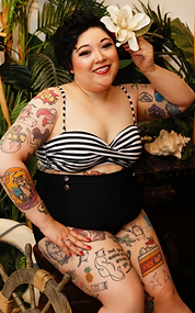 Tia in a retro swimsuit, showing off her tattoos