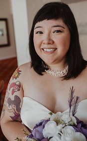 Tia in a wedding dress, holding a white and lavender bouquet