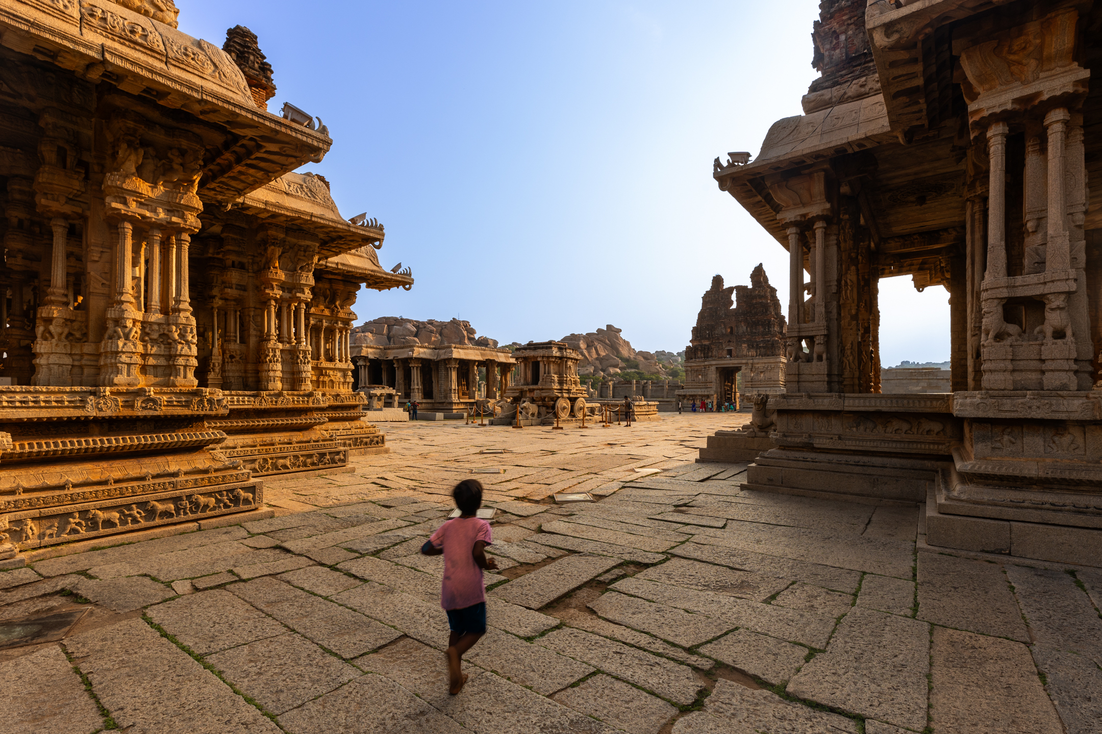 A child running through ancient temple architecture at Hampi