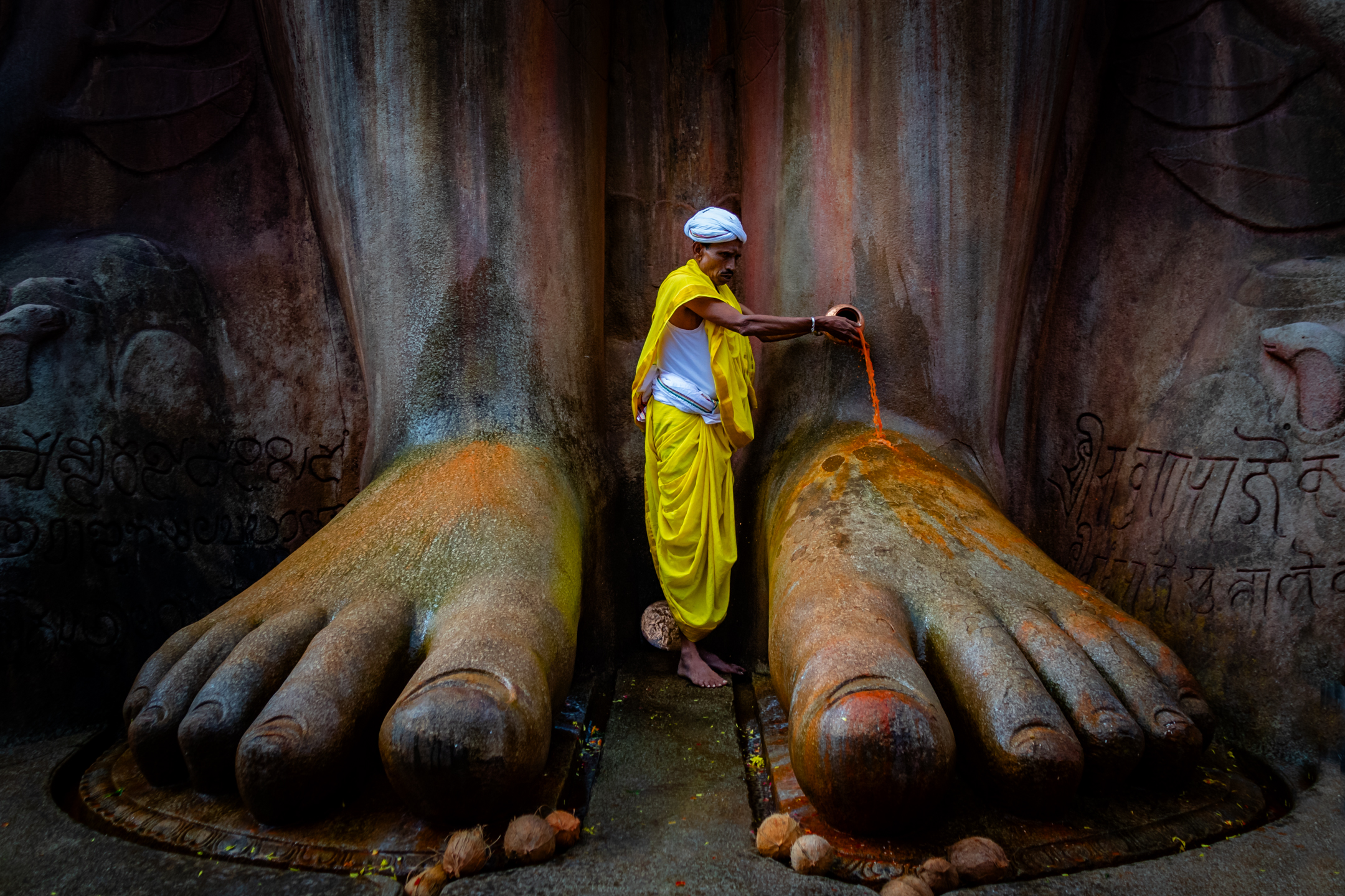 A worshipper ceremonially washes the feet of the Bahubali statue at Shravanabelagola