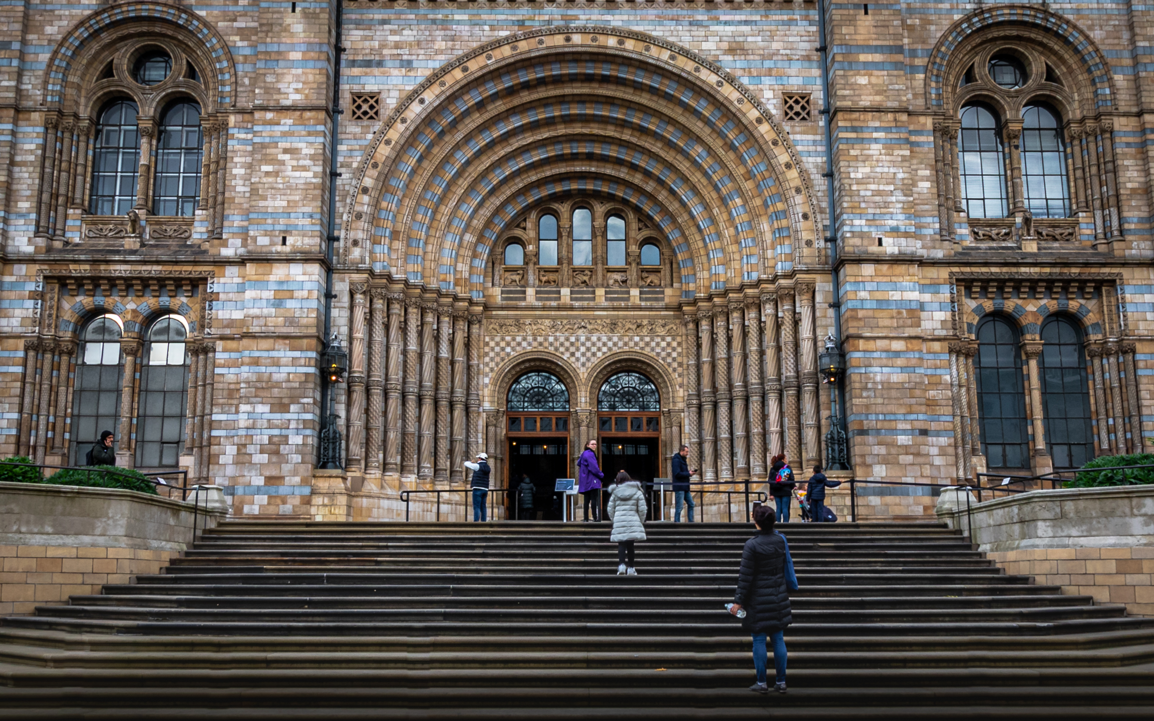 People seated on broad steps at an ornate entrance