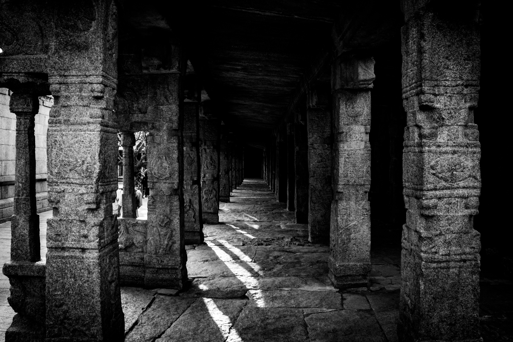 A dark stone corridor with shafts of daylight revealing its texture