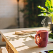 Modern remote work setup with laptop and steaming coffee in a sunlit home office, showcasing an AI-powered work-from-anywhere vacation lifestyle.
