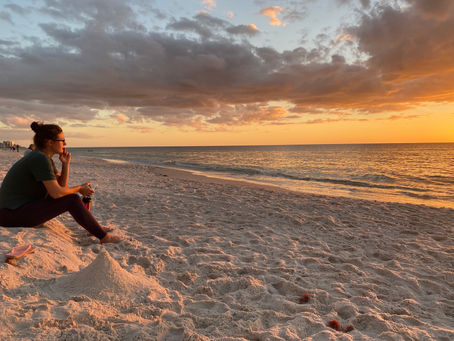 Woman gazing out at sunset over ocean