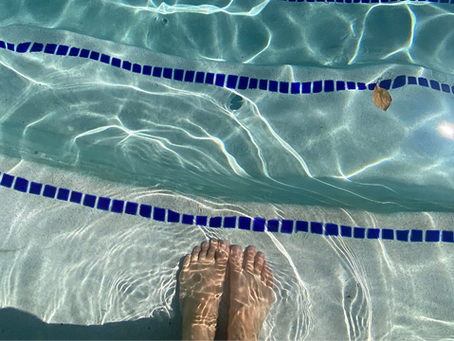Woman's feet underwater on pool steps