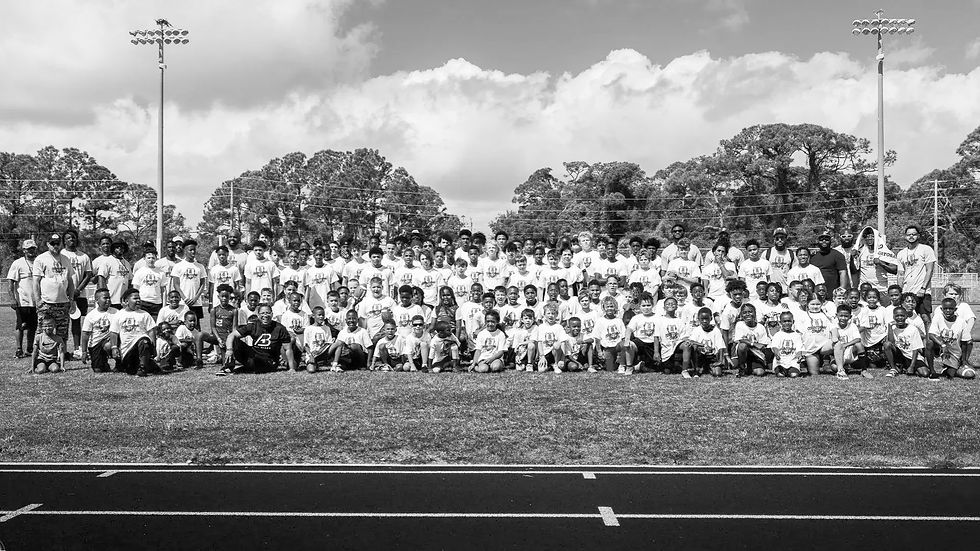 A large group of children and adults in matching shirts posing on a field.