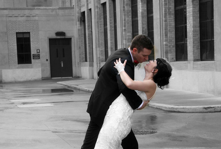 A groom dipping his bride infront of a building. Picture captured by Scarfone Imaging, professional photography services in Niagara Ontario.
