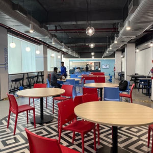 Modern cafe with red chairs and round tables.