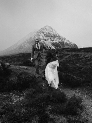 Husband laughing while helping his wife up a steep mound